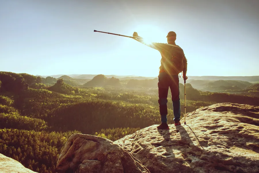 En mann som står på en stein med en pinne i hånden
