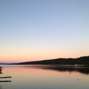 En vannmasse med trær og åser i bakgrunnen