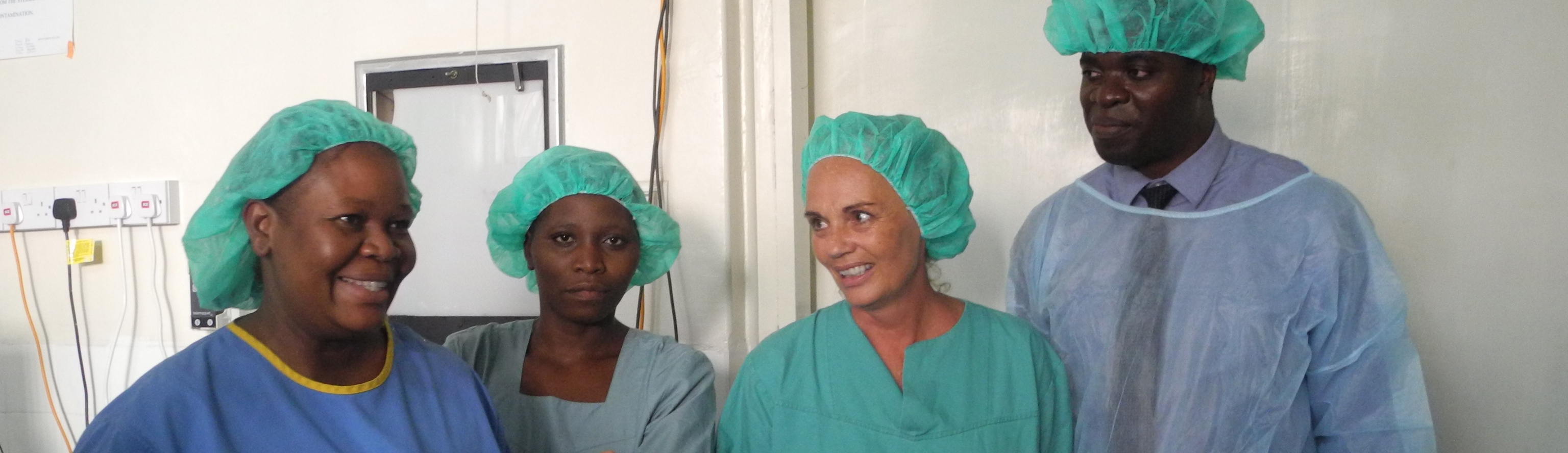 Fire stykker helsepersonell står kledd i grønt.