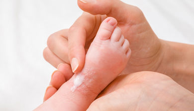 En hånds smører foten på baby