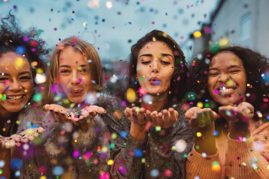 Fire unge jenter som blåser glitter ut i luften.