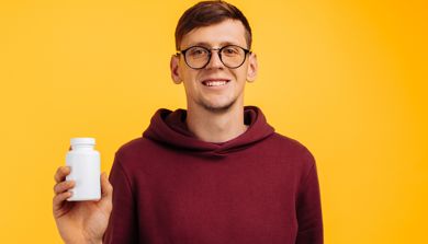 Smilende mann som holder en pilleboks