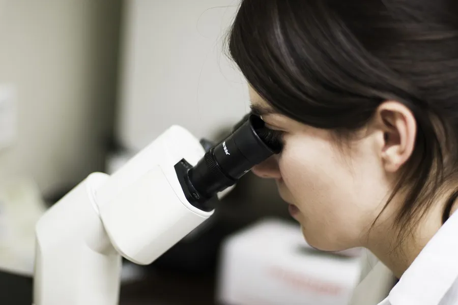 Bilde av en som ser i et mikroskop