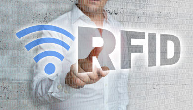 En person som står bak et glass og peker på teksten RFID.