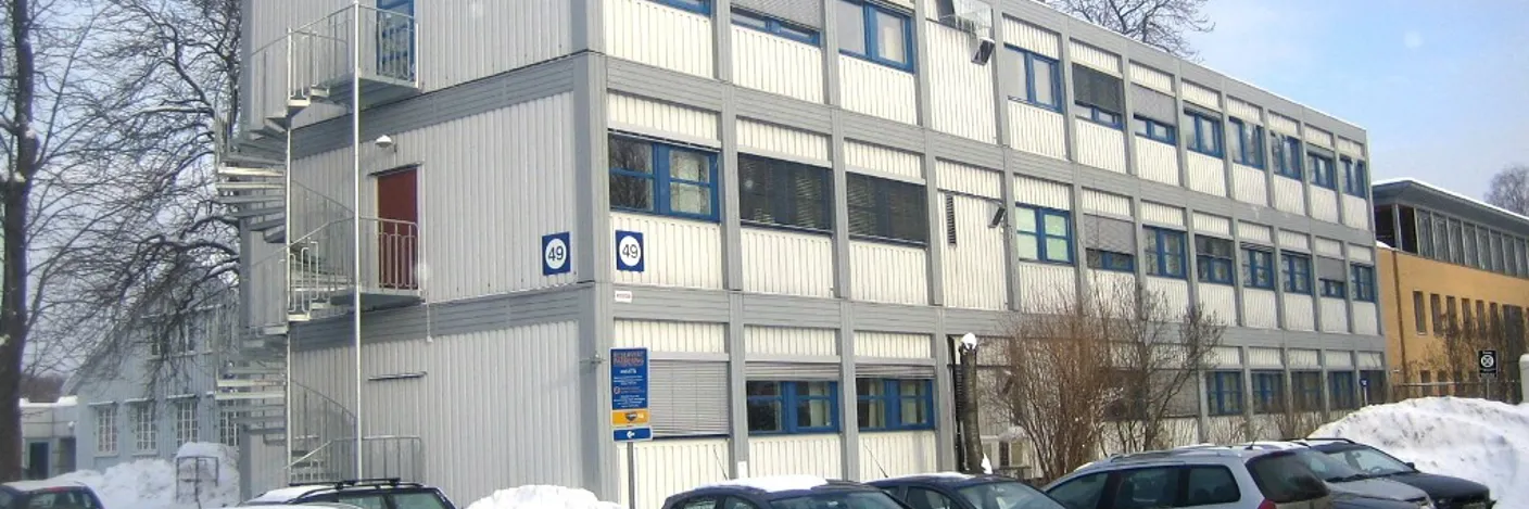 En parkeringsplass foran en bygning med snø på bakken