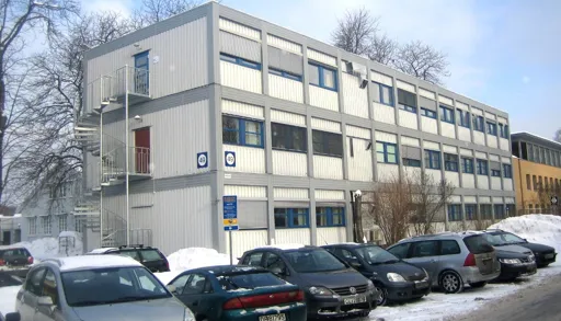 En parkeringsplass foran en bygning med snø på bakken