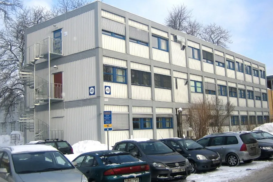 En parkeringsplass foran en bygning med snø på bakken