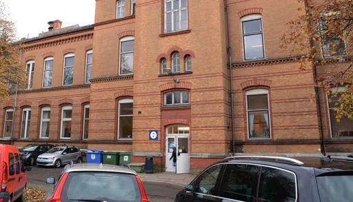 En murbygning med biler parkert foran