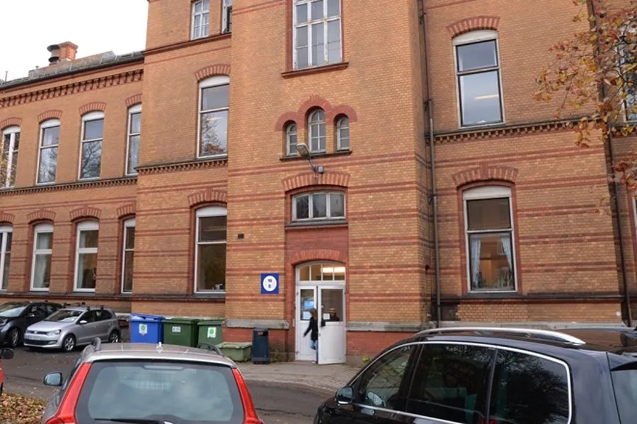 En murbygning med biler parkert foran