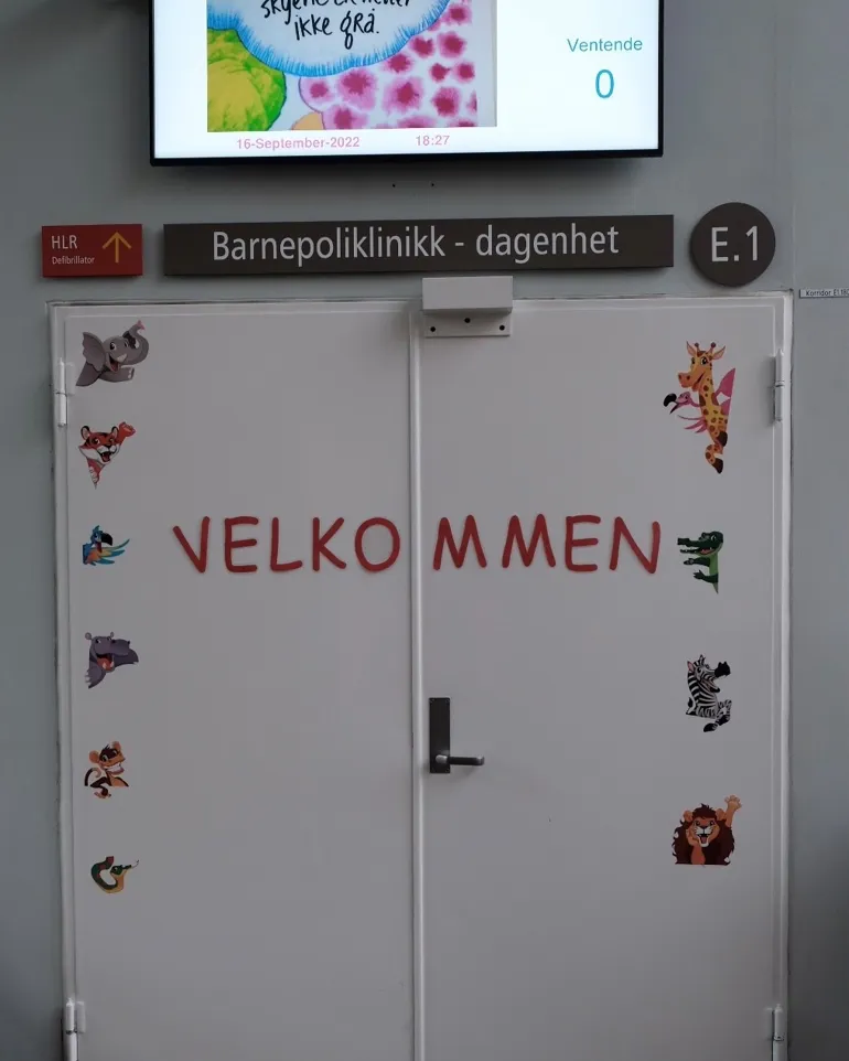 Inngangsdøren til barnepoliklinikken. På døren står det "Velkommen" med dyreklistremerker.