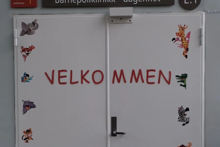 Inngangsdøren til barnepoliklinikken. På døren står det "Velkommen" med dyreklistremerker.