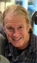 Portrettbilde av Richard Olsen som smiler opp mot kameraet med hestehale.