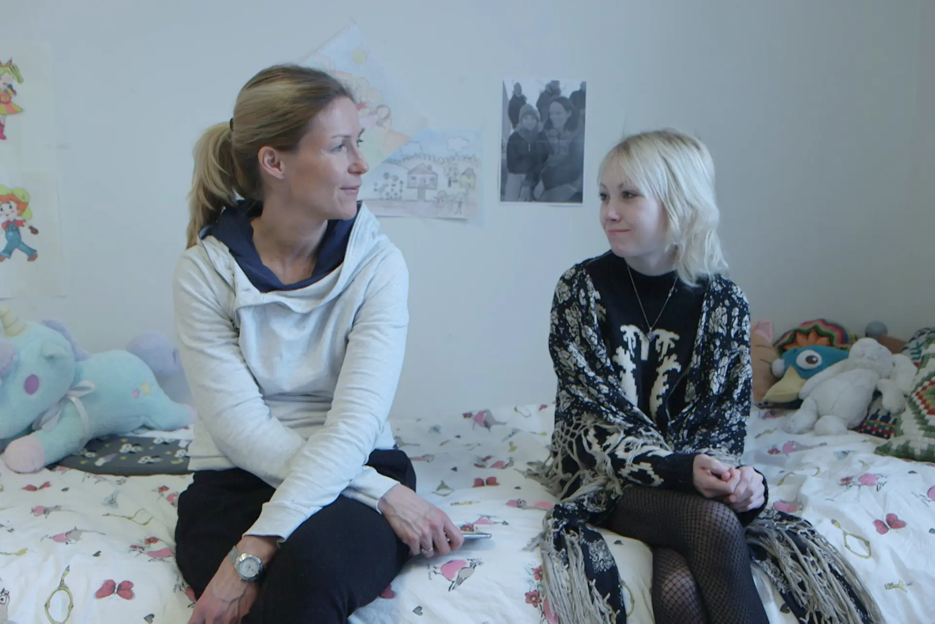 En kvinne som sitter ved siden av en kvinne på en seng