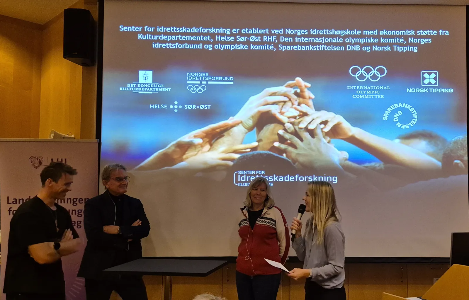 En gruppe mennesker som står foran en skjerm