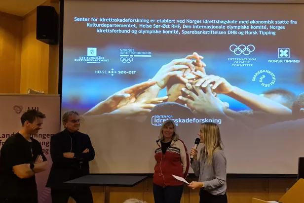En gruppe mennesker som står foran en skjerm
