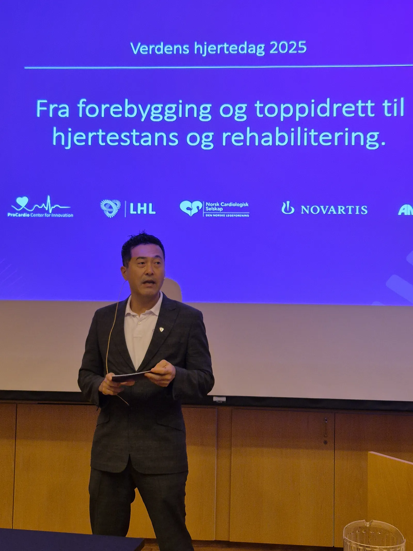 En mann som står foran en skjerm med blå bakgrunn