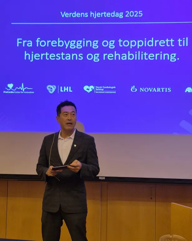 En mann som står foran en skjerm med blå bakgrunn