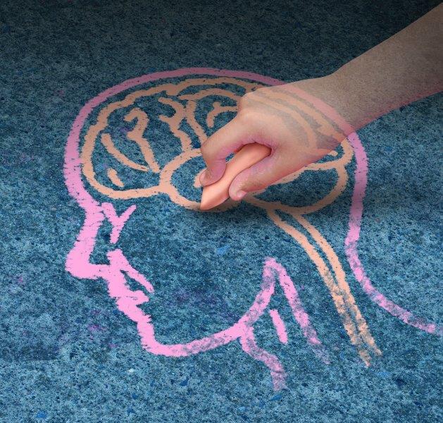 A hand is drawing a brain with chalk on the tarmac