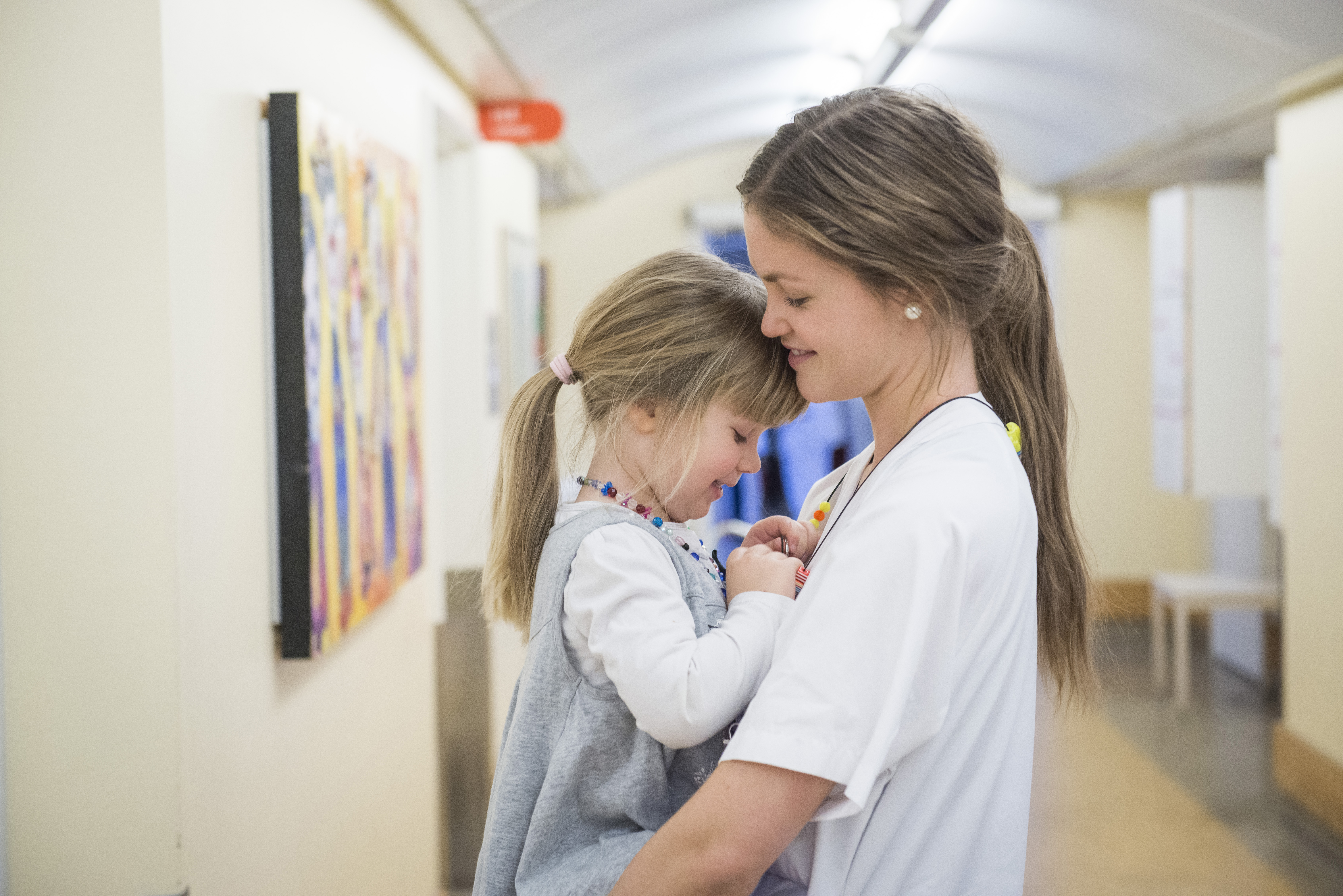 En sykepleier som holder en jente i armene sine. De smiler til kameraet.