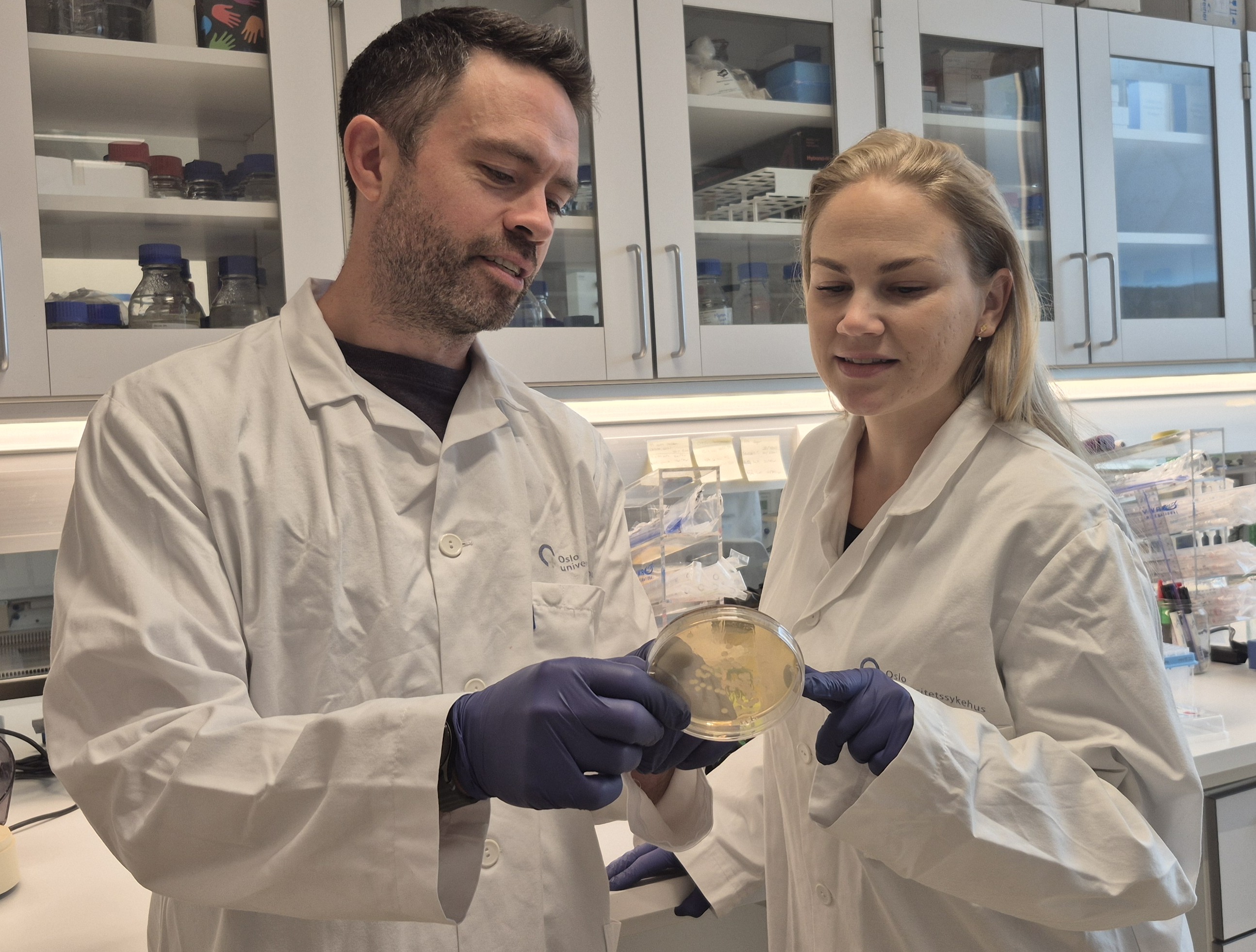 En mann og en kvinne i laboratoriefrakker som ser på et eksemplar