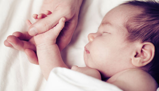 Baby som holder mors hånd.