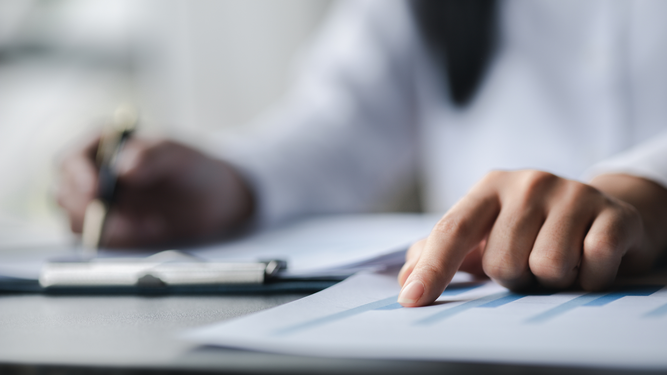 Nærbilde av en person som skriver på et stykke papir