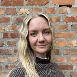 Kvinne foran en murvegg