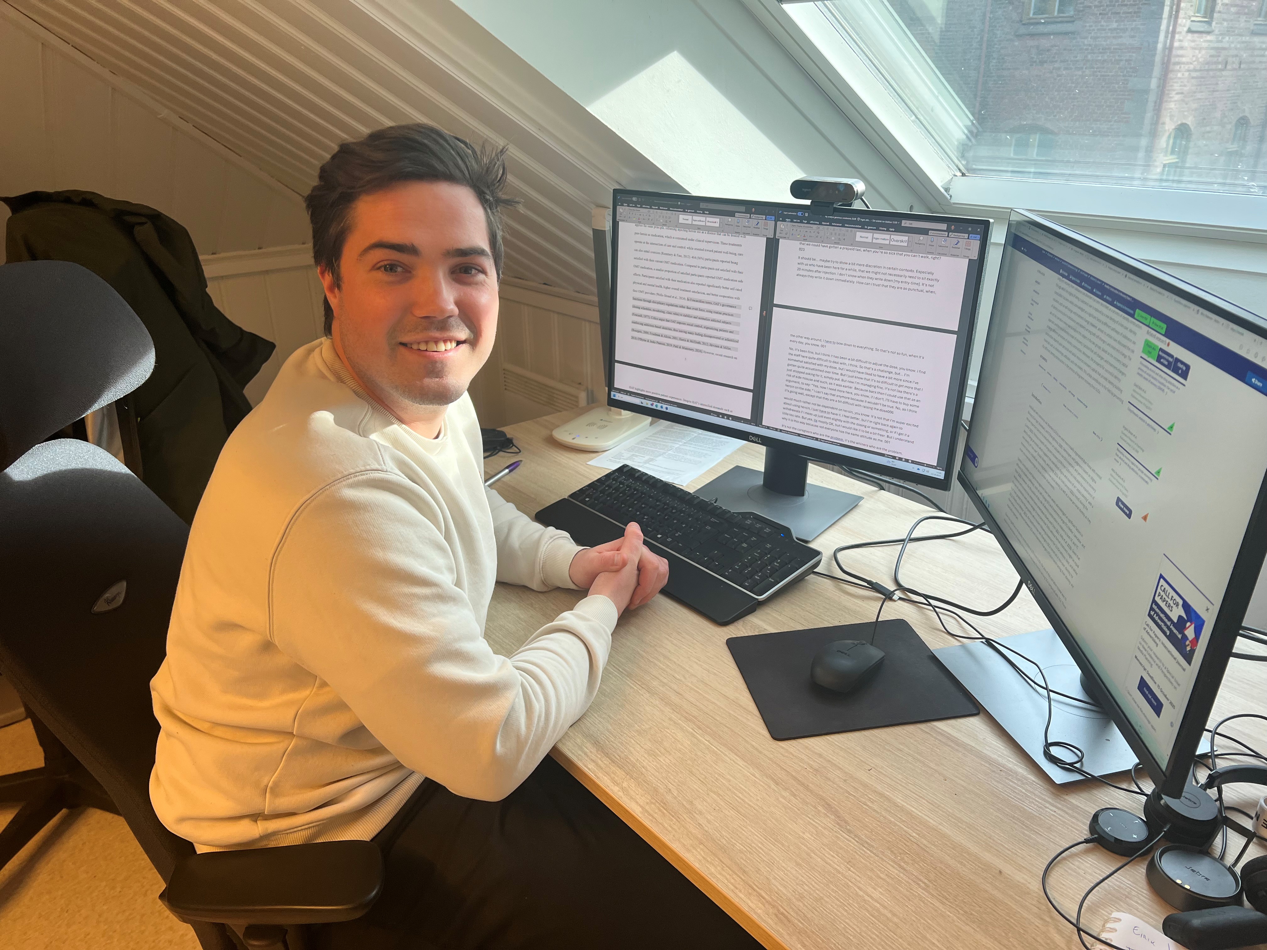 En forsker sitter ved et skrivebord med flere skjermer