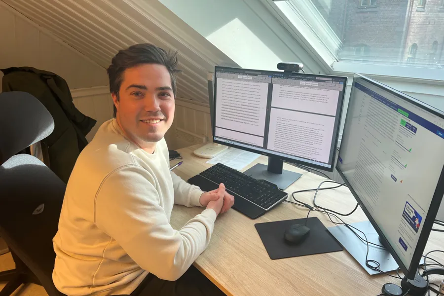 En forsker sitter ved et skrivebord med flere skjermer