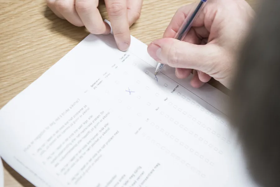 Hender som signerer et ark