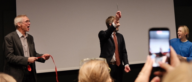 En mann som holder en mikrofon og en kvinne som står foran en projektorskjerm