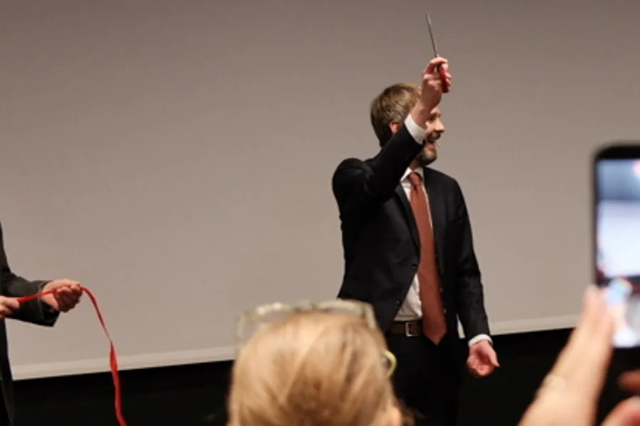 En mann som holder en mikrofon og en kvinne som står foran en projektorskjerm