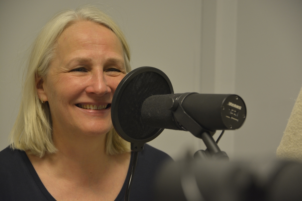 En kvinne som smiler og holder en mikrofon