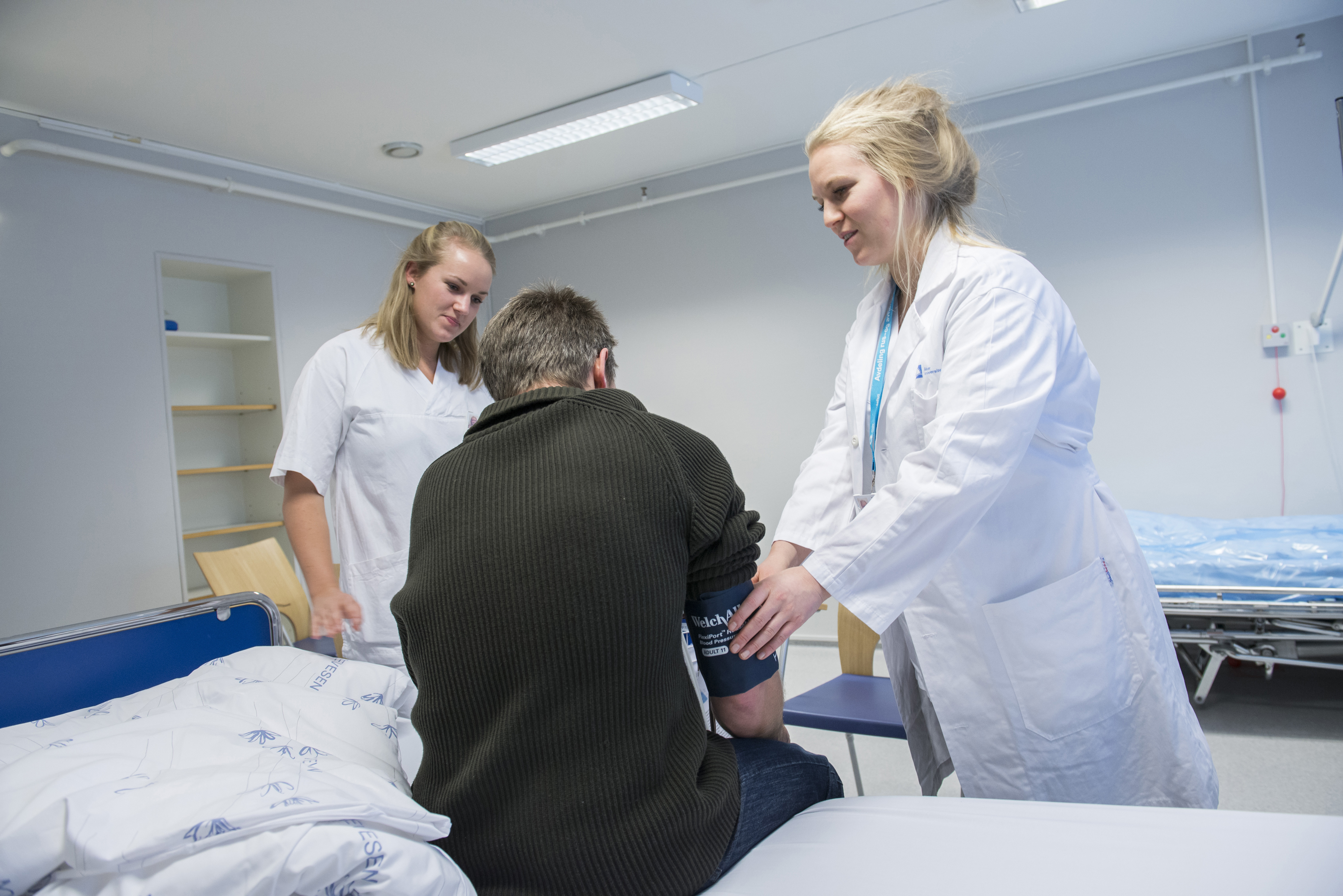 Pasient i seng får hjelp av sykepleiere