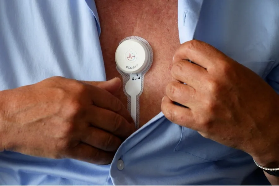 En mann som holder en hvit enhet