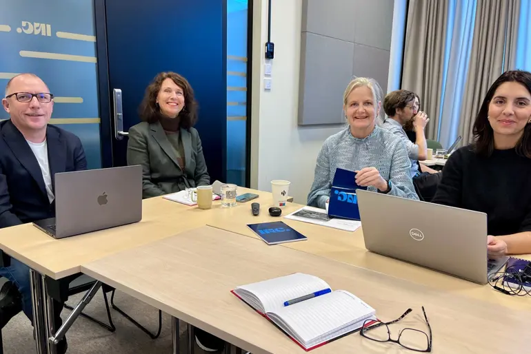 En gruppe mennesker som sitter rundt et bord med bærbare datamaskiner