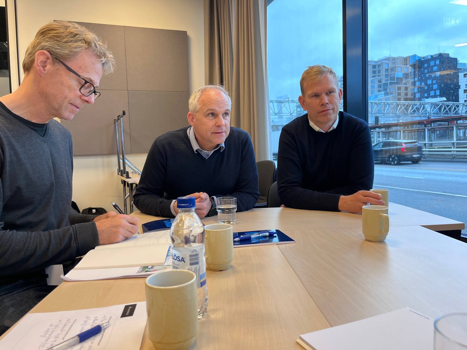 En gruppe menn som sitter ved et bord og ser på papirer