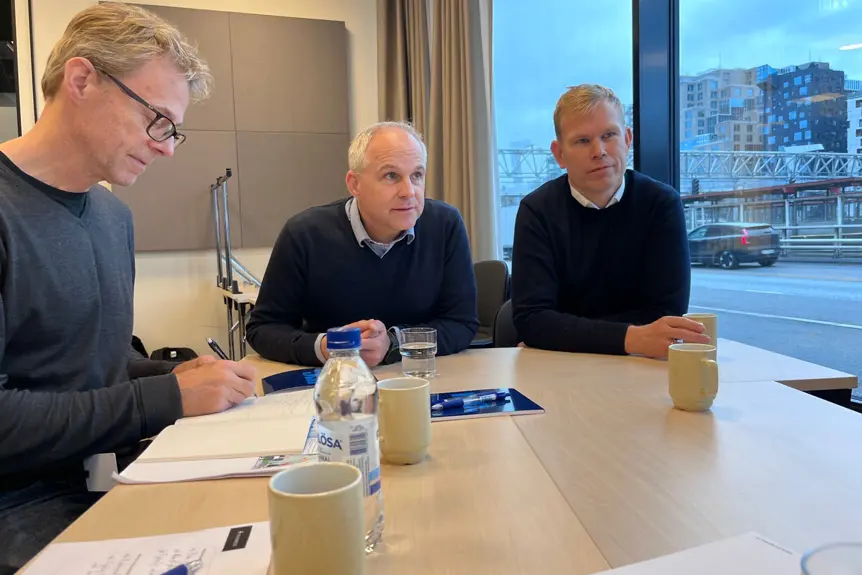 En gruppe menn som sitter ved et bord og ser på papirer