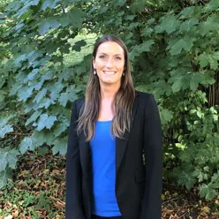 A woman standing in front of a bush