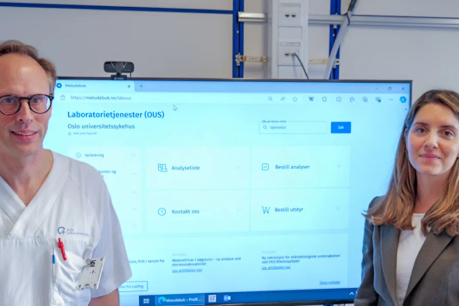 En mann og en kvinne som står foran en dataskjerm