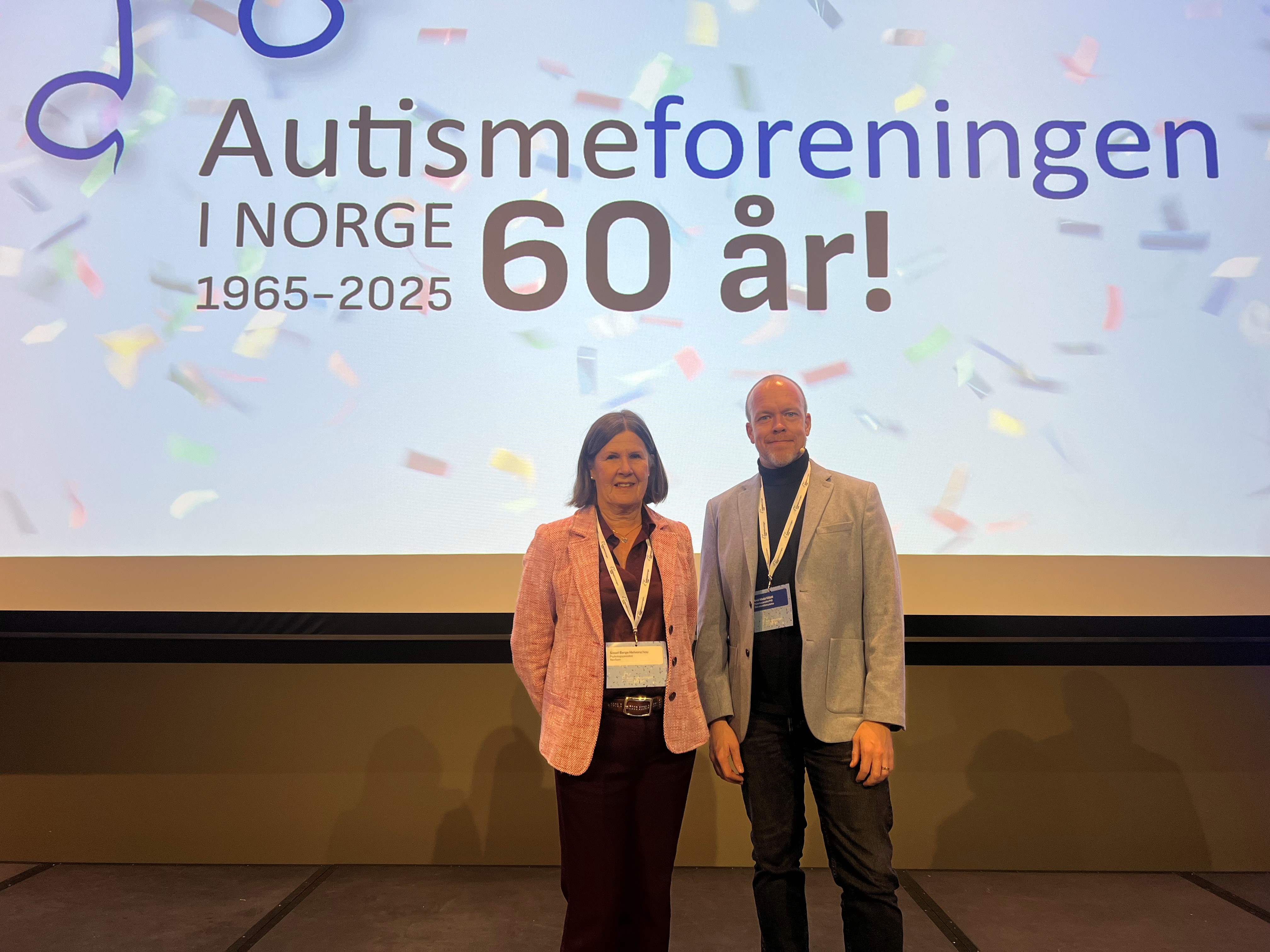 En mann og kvinne som står foran en storskjerm