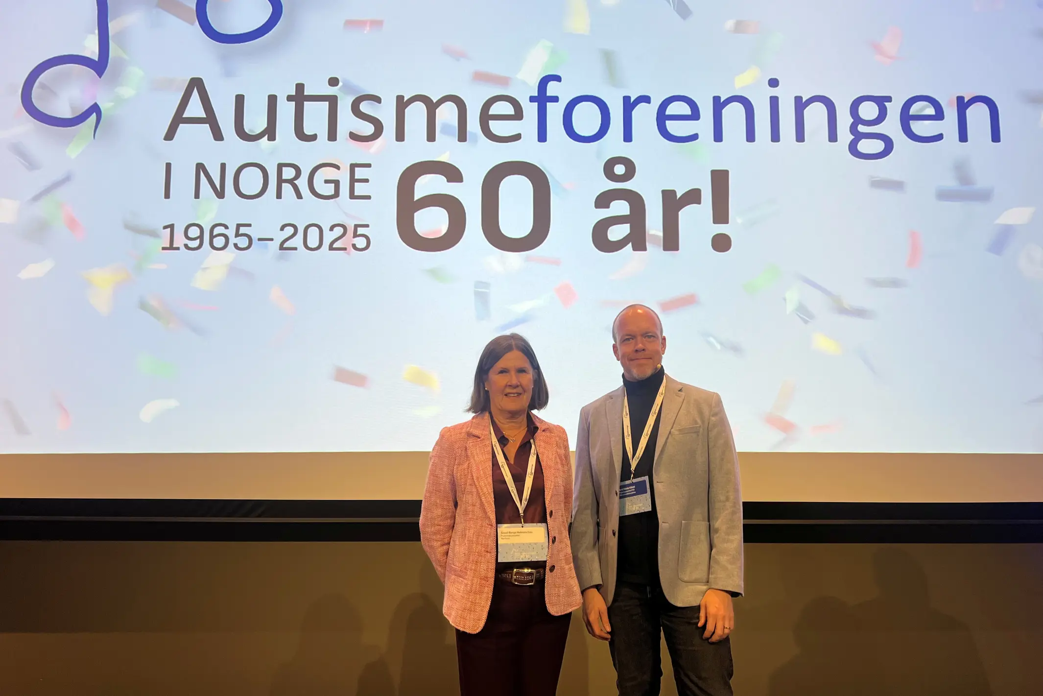 En mann og kvinne som står foran en storskjerm