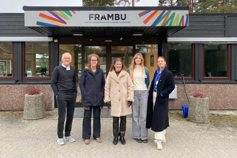 En gruppe mennesker som poserer for et bilde foran en bygning