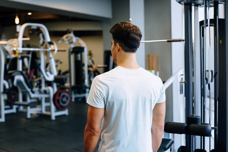 En mann i et treningsstudio som ser på treningsapparater