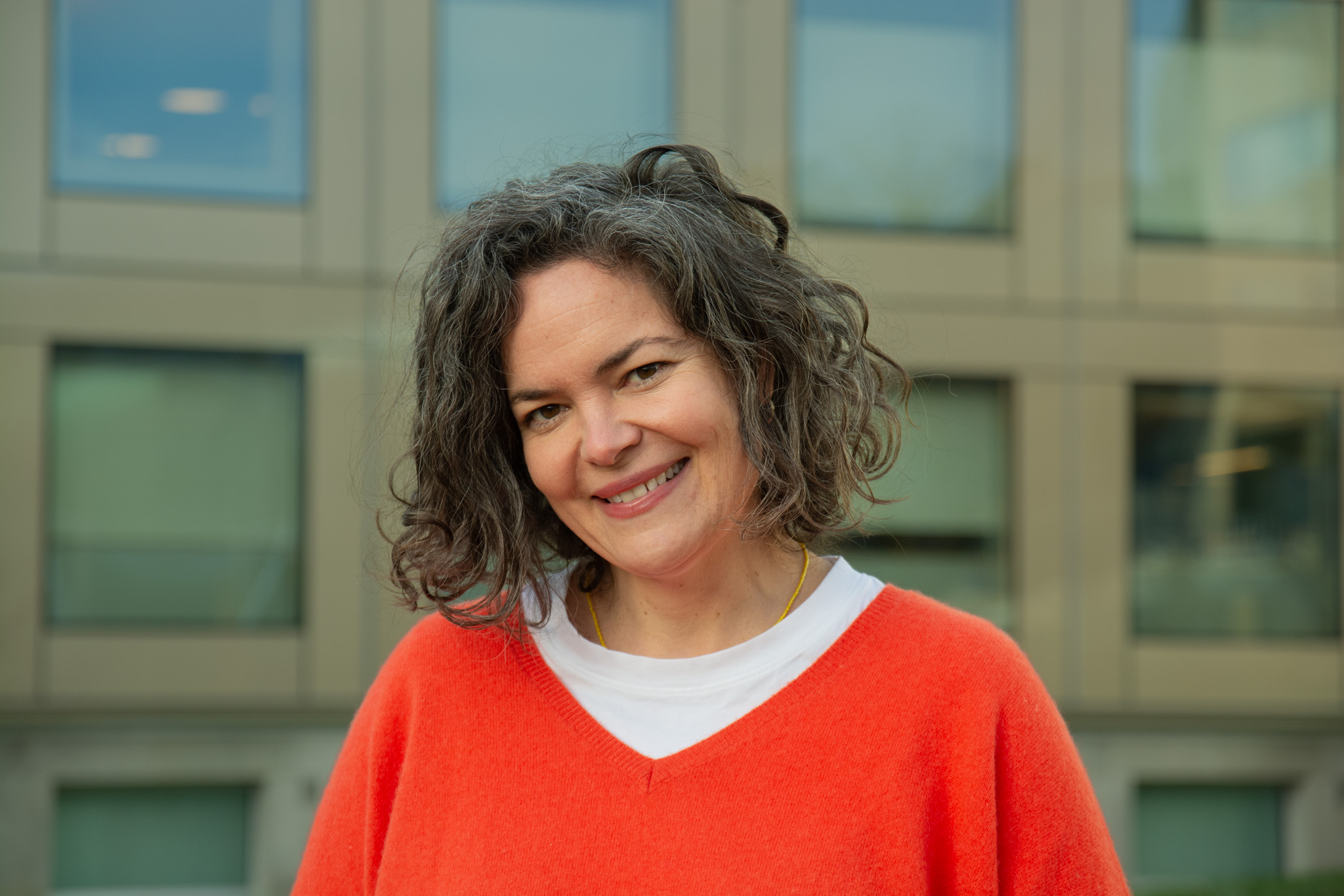 En person som smiler foran en bygning