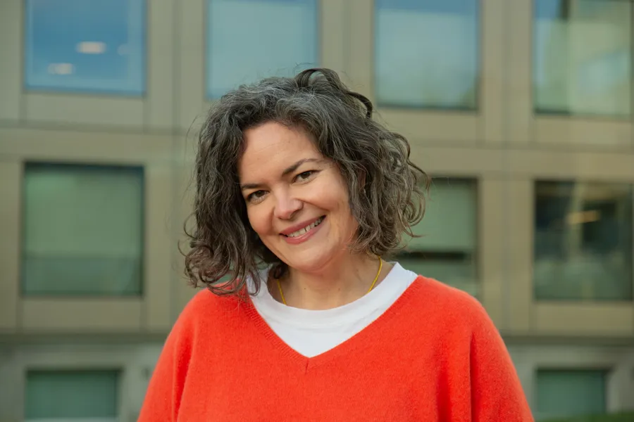 En person som smiler foran en bygning