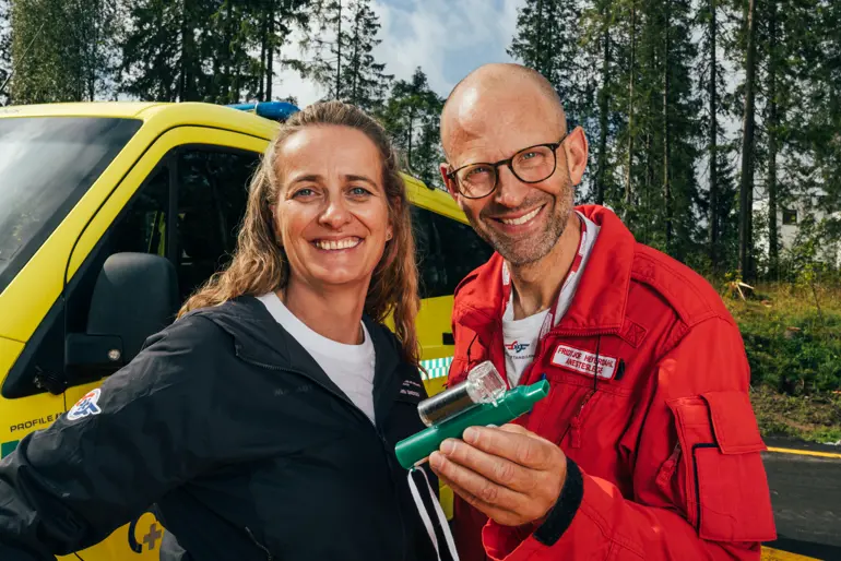 Bilde av to personer utenfor en ambulanse som holder medisinsk utstyr