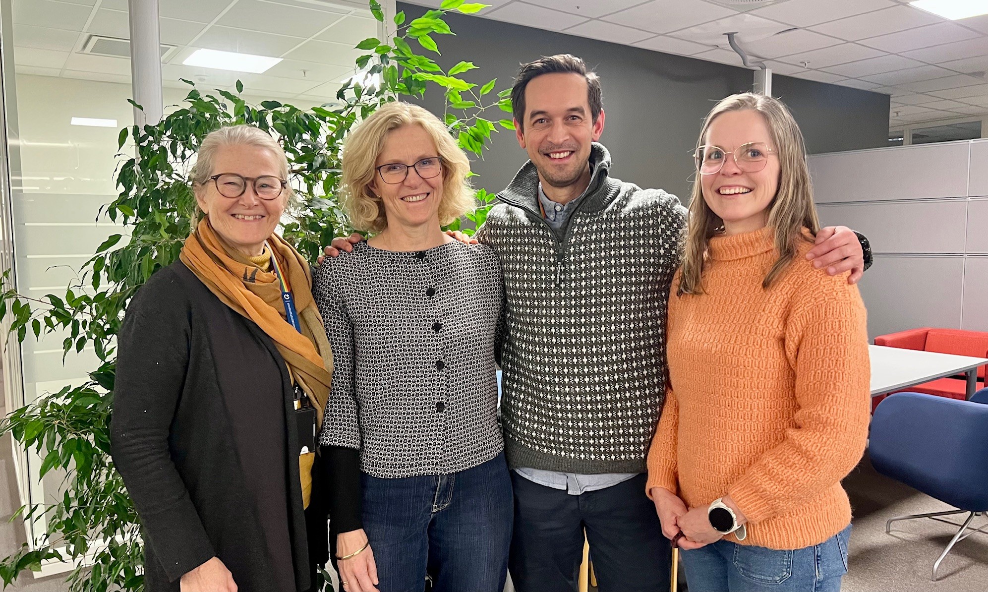Kristin Bjordal, Cecilie Delphin Amdal, Kenth-Louis Hansen Joseph og Ragnhild Sørum Falk står inntil hverandre på kontoret og smiler mot kameraet.