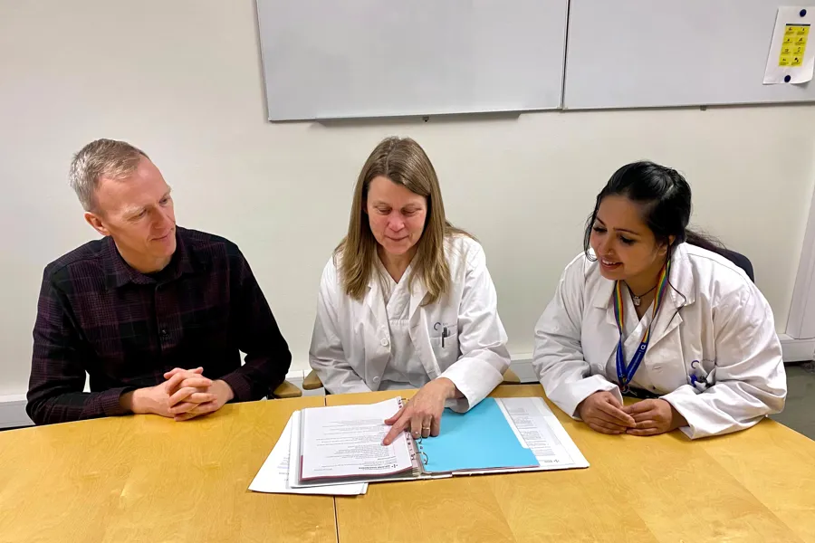 En gruppe mennesker som sitter ved et bord og ser på et papir