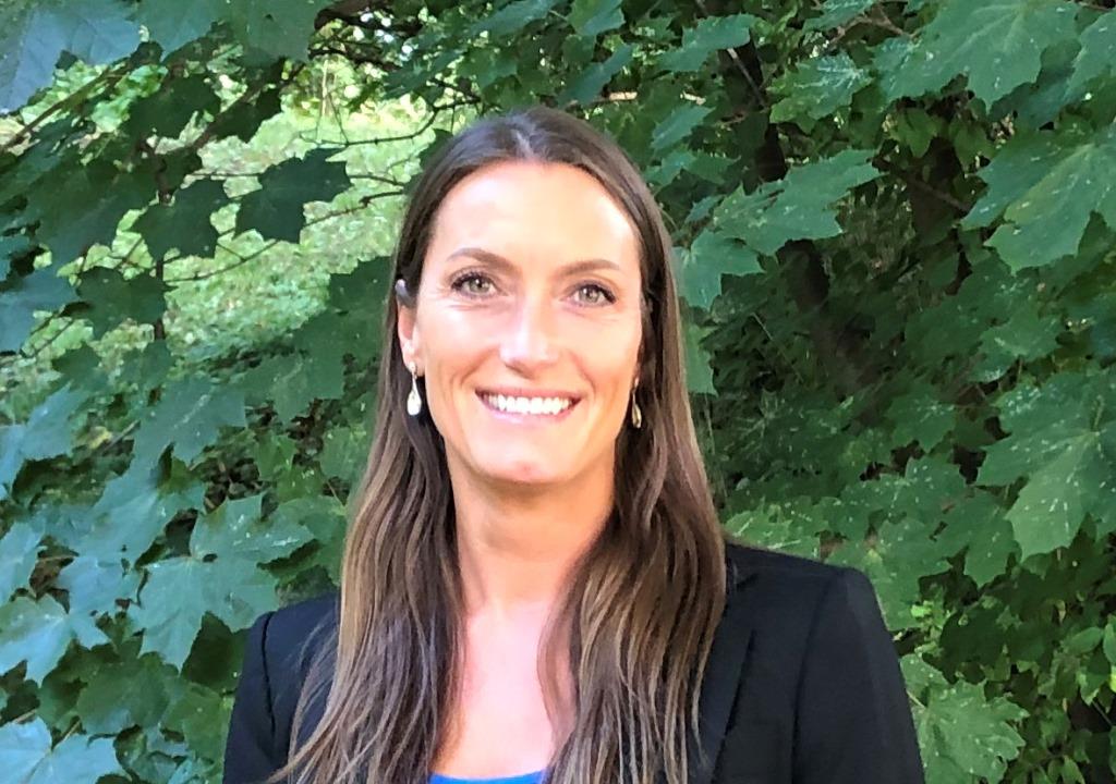 En person som smiler foran en busk